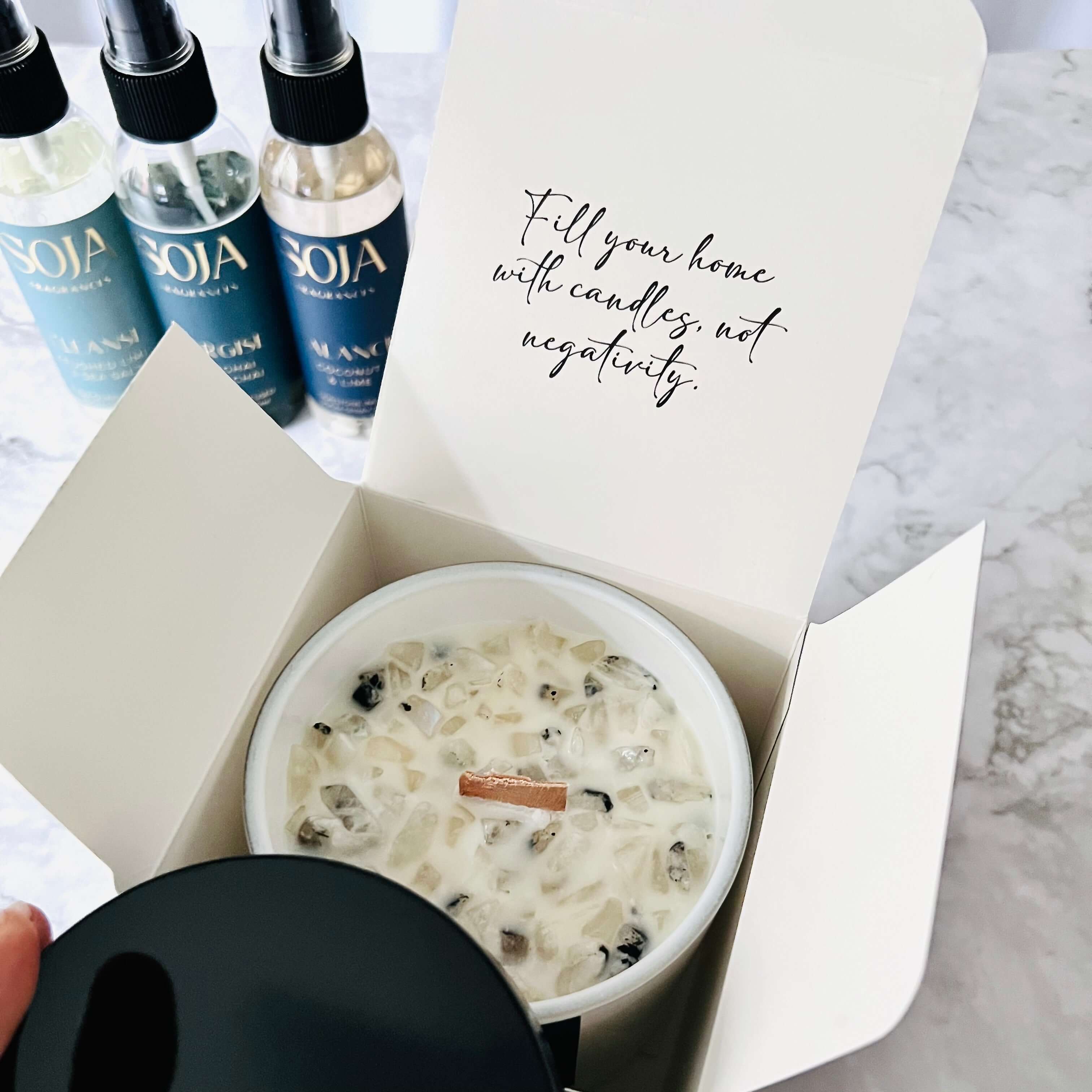 Crystal-infused candles with their corresponding raw stones placed in a calming home setting.