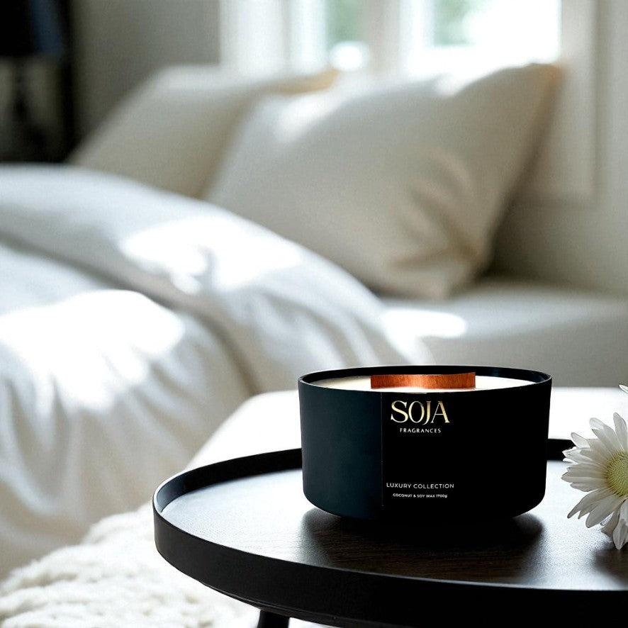 Black candle with 'SOJA' branding on a white surface