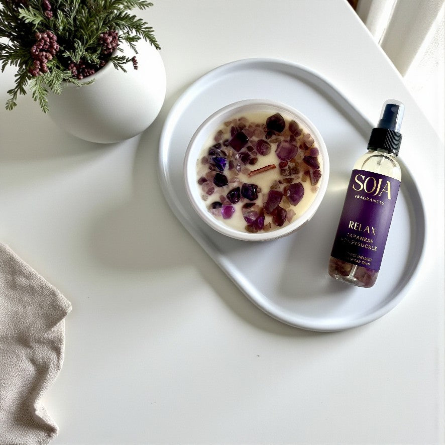 SOJA Fragrances product set including a bottle, box, and candle on a reflective surface with a light gray background.