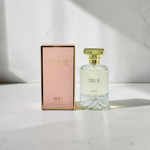 Perfume bottle and packaging with 'TRUE' branding on a light background