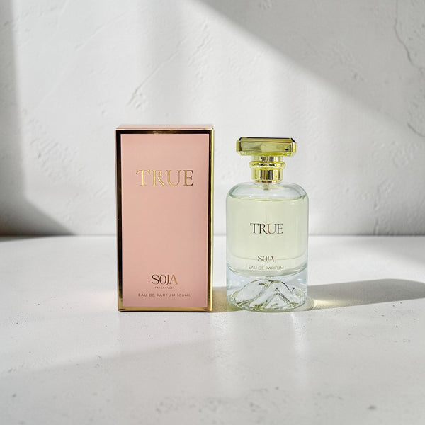 Perfume bottle and packaging with 'TRUE' branding on a light background