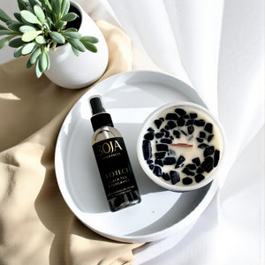 Candle and matching room spray 'SOJA' on a white plate with a bowl of black and white dessert.