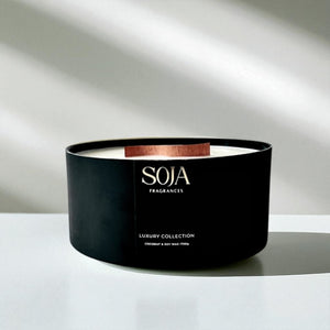 Black candle with 'SOJA' branding on a white surface