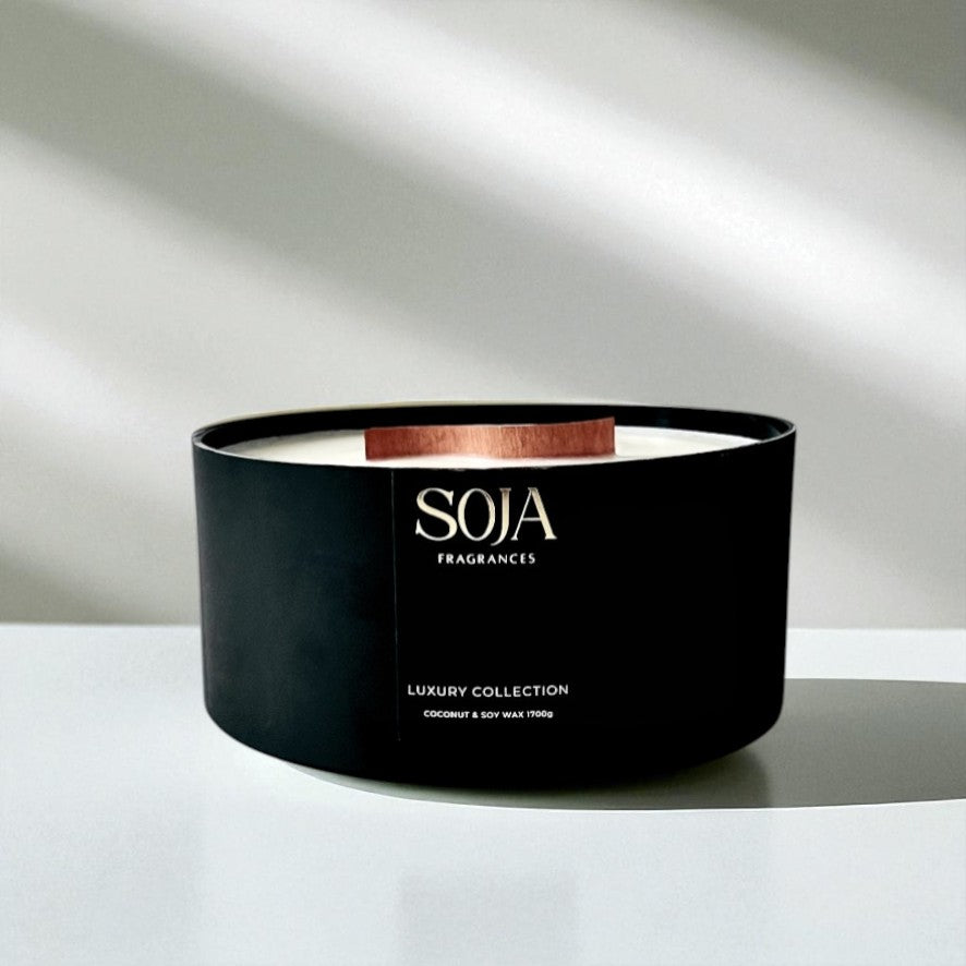 Black candle with 'SOJA' branding on a white surface