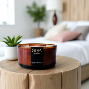 Candle with 'SOJA' branding on a wooden table in a cozy living room setting.