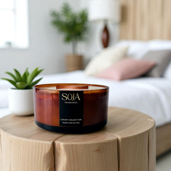 Candle with 'SOJA' branding on a wooden table in a cozy living room setting.
