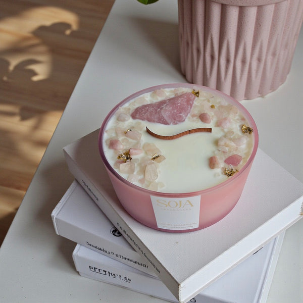 Pink candle with decorative elements on a stack of books