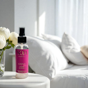 Spray of  SOJA Fragrance on a table with flowers and a white couch in the background