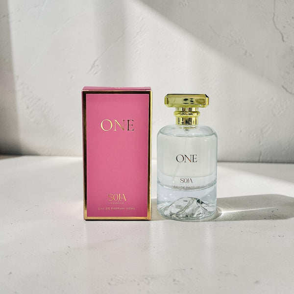 Perfume bottle and packaging with 'ONE' branding on a light surface.