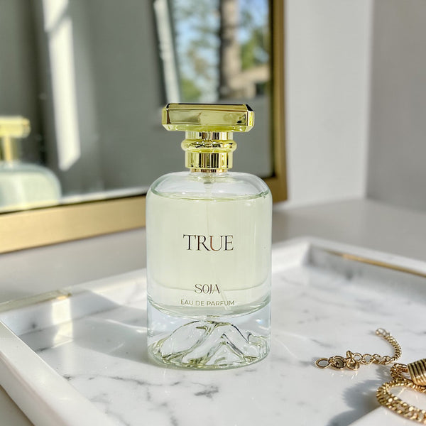 Perfume bottle labeled 'True Soja' on a marble surface with a blurred background