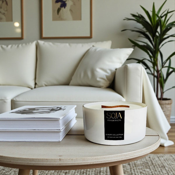 Candle on a coffee table with a stack of books and a plant in the background