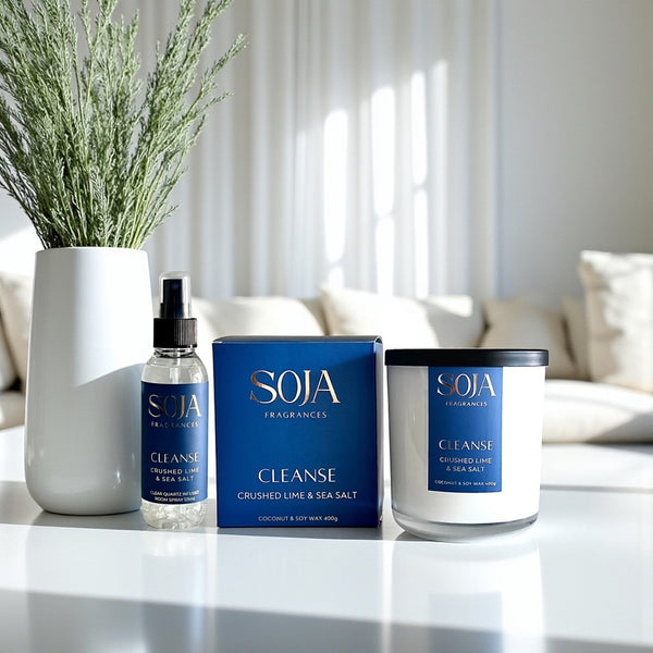 SOJA Fragrances 'Cleanse' products on a table with a vase of plants in the background.
