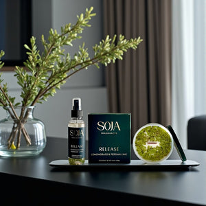 SOJA Fragrances products including a bottle, box, and room spray on a table with a plant in the background.