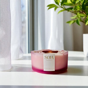Pink luxury candle on white counter with flowers
