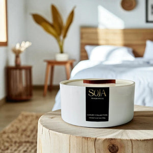 White SOJA candle on a wooden surface in a bedroom setting
