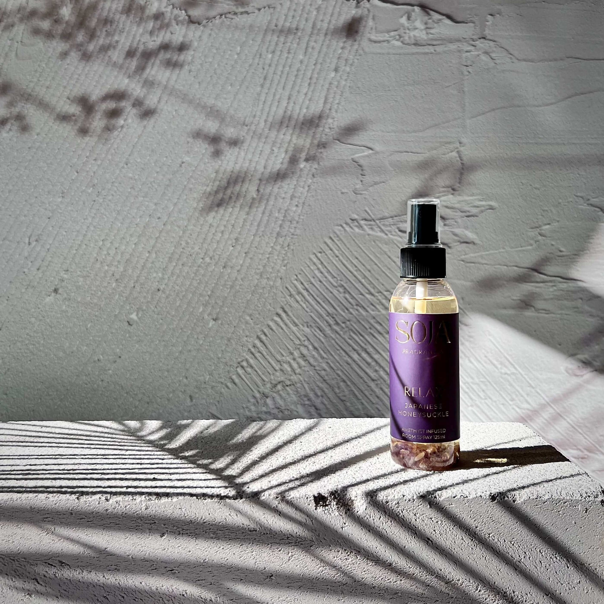 Relax Amethyst crystals perfume room spray japanese honeysuckle on stone block in sunlight