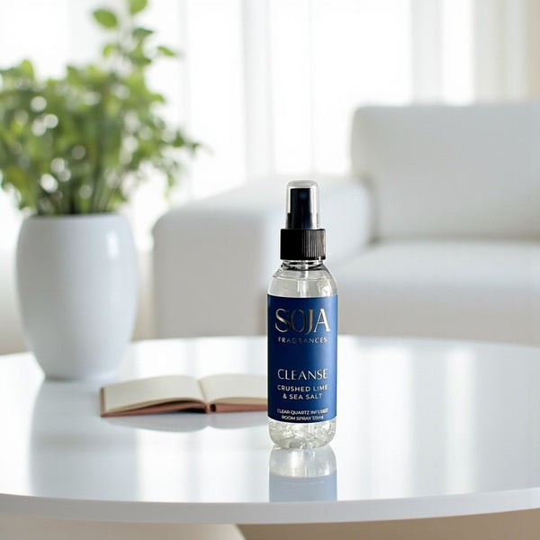 Room Spray SOJA Fragrances on a white surface with a plant and book in the background