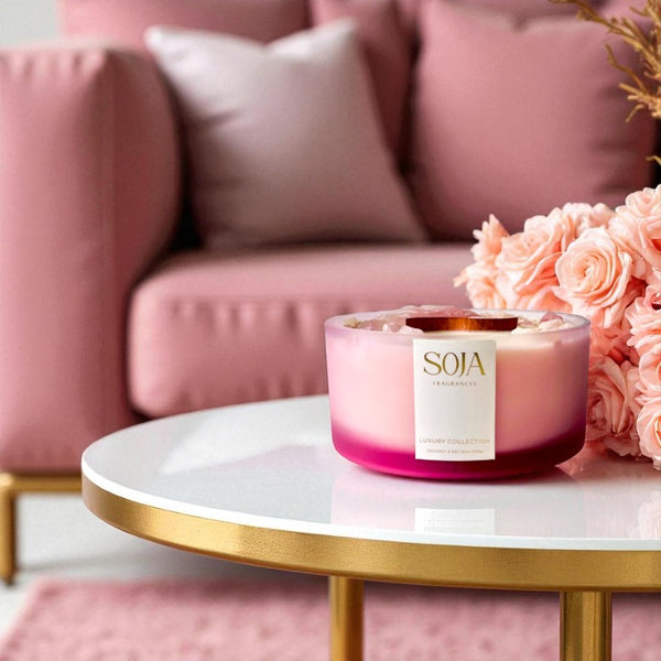 Pink candle with 'SOJA' branding on a marble table in a living room setting.