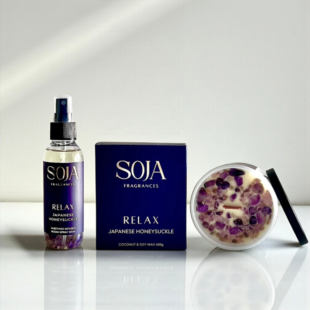 SOJA Fragrances product set including a bottle, box, and candle on a reflective surface with a light gray background.
