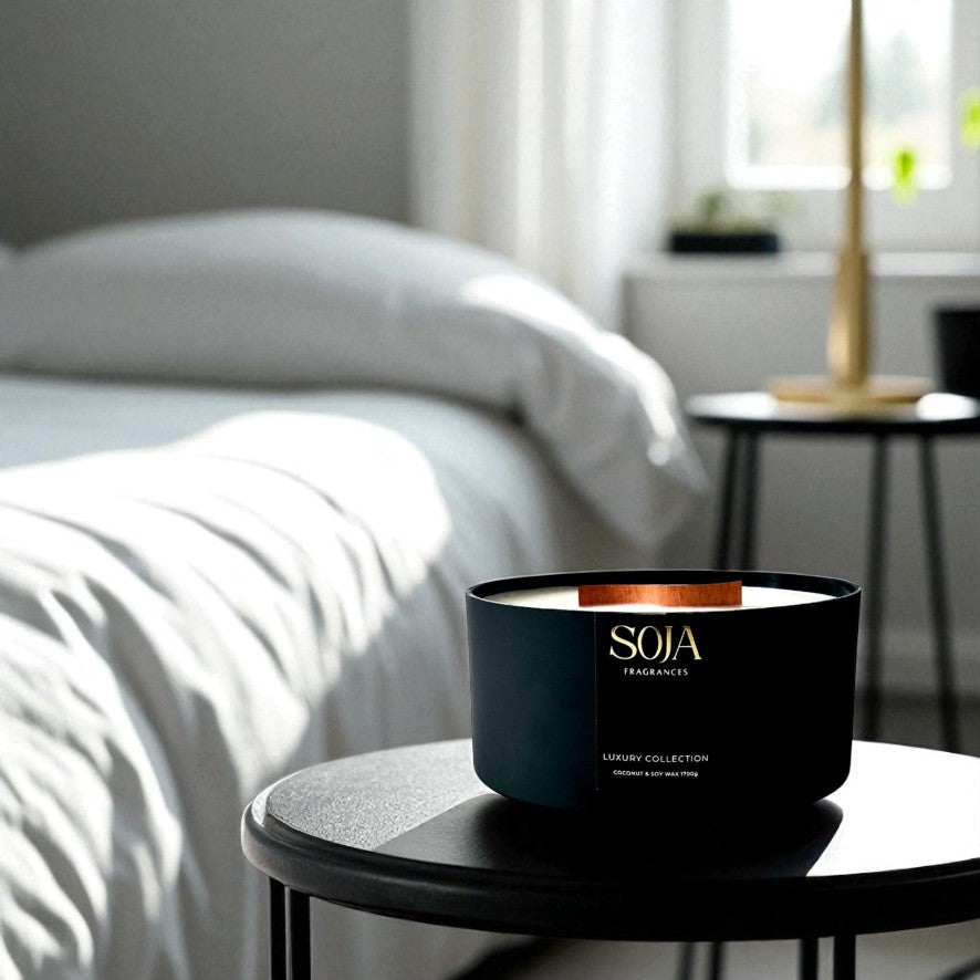 Black candle with 'SOJA' branding on a white surface