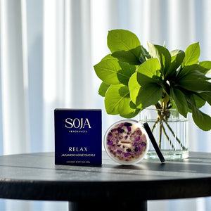 Relax Japanese Honeysuckle crystal candle styled on table with deep purple box and greenery