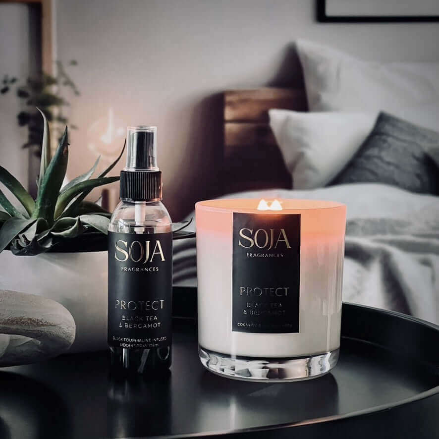 black tourmaline black tea and bergamot scented perfumed candle on tray in bedroom with plant